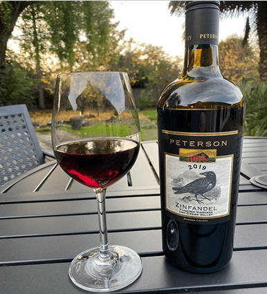 Peterson Winery wine bottle and wine glass with vineyard grapes